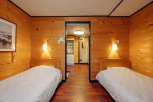 two beds in a room with wooden walls at Hotel Morgenrot in Kobe