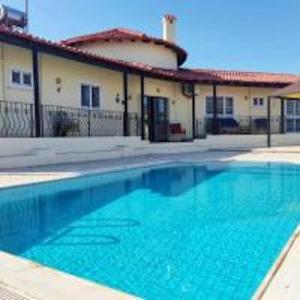 a large blue swimming pool in front of a building at Beach Villa in Saint Epiktitos