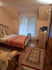 a bedroom with two beds and a window and a rug at Casa Maia Dambovicioara in Dâmbovicioara