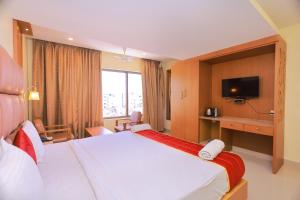 um quarto de hotel com uma cama grande e uma televisão em Hotel Sangam em Kanyakumari