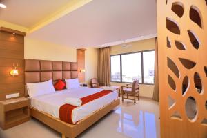 a hotel room with a bed and a large window at Hotel Sangam in Kanyakumari