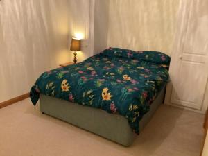 a bed with a green comforter with flowers on it at polgoon Vineyard annex Penzance in Penzance