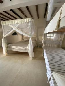 a bedroom with two bunk beds with white sheets at Coral Village in Malindi