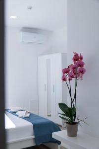 a vase with pink flowers on a table in a bedroom at Essentia Rooms & Relax in Vasto