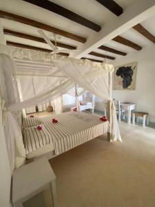 um quarto com uma cama branca com rosas vermelhas em Coral Village em Malindi