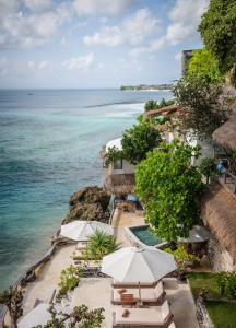 an outdoor swimming pool with umbrellas and the ocean at Rock'n Reef in Uluwatu