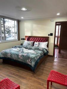 a bedroom with a large bed with a red headboard at Hotel Jakhu Heights in Shimla