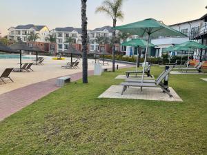 a park with benches and umbrellas next to a pool at Contemporary unit at the Blyde in Pretoria