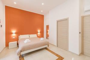 een slaapkamer met een bed en een oranje muur bij O' Munasterio e Santa Chiara in Napels +21 foto's