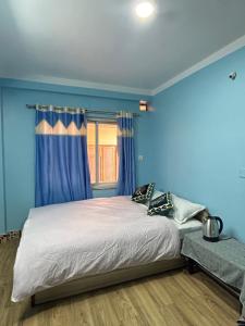 a bedroom with a bed with blue walls and a window at Sagarmatha View Homes in Kathmandu