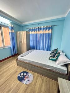 1 dormitorio con 1 cama con paredes azules y suelo de madera en Sagarmatha View Homes, en Katmandú