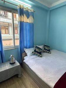 um quarto com uma cama com paredes azuis e uma janela em Sagarmatha View Homes em Kathmandu