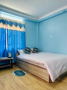 um quarto com paredes azuis e uma cama com almofadas em Sagarmatha View Homes em Kathmandu