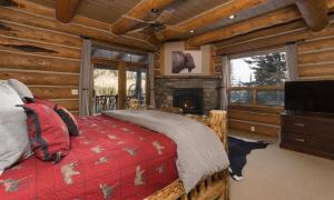 MV Souvenirs Lodge في بيغ سكاي: غرفة نوم مع سرير ومدفأة في كابينة خشب