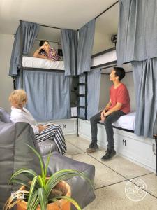 grupa osób siedzących na łóżkach piętrowych w obiekcie DeRequka Hostel w mieście Pereira