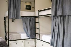 2 Etagenbetten in einem Schlafzimmer mit blauen Vorhängen in der Unterkunft DeRequka Hostel in Pereira
