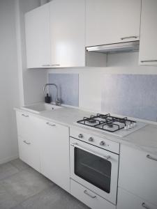 a white kitchen with a stove and a sink at Ceccarini 2023 in Riccione