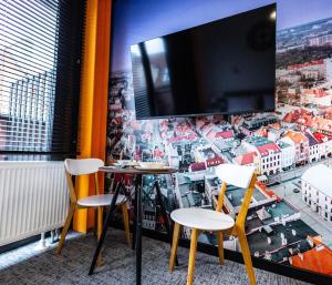 a room with two chairs and a tv on a wall at Apartamenty Plebańska-Rynek in Gliwice