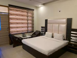 a bedroom with a bed and a desk and a window at Hotel Citi Heights in Chandīgarh