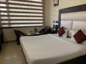 Un dormitorio con una gran cama blanca y sillas en Hotel Citi Heights, en Chandīgarh
