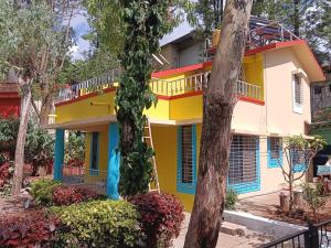 a colorful house in the middle of trees at Om Bungalow -Happy Stay At Panchgani in Panchgani