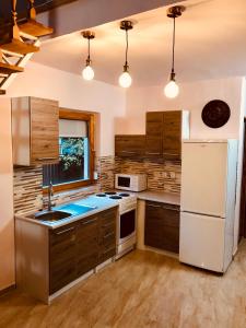 a kitchen with wooden cabinets and a white refrigerator at Tieffapartmanház Balatonszárszó in Balatonszárszó +27 photos