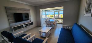 a living room with a blue couch and a television at Perlemoen 301 in Hartenbos