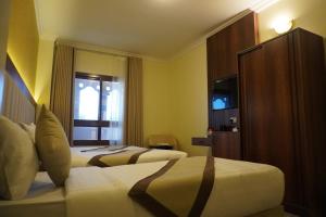 a hotel room with two beds and a television at Roaa Al Andalus Hotel فندق رؤى الاندلس in Al Madinah
