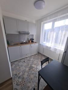 a kitchen with white cabinets and a table and window at Modern Studio flat(dedicated) in Vilnius