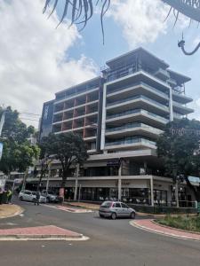 un grand bâtiment avec des voitures garées devant lui dans l'établissement Trendy Apartment, à Durban