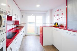 une cuisine avec des placards blancs et des comptoirs rouges dans l'établissement Apartamentos GO - Arroyo Ático Regato, à Arroyo de la Encomienda