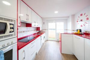 una cocina con armarios blancos y encimeras rojas en Apartamentos GO - Arroyo Ático Regato, en Arroyo de la Encomienda