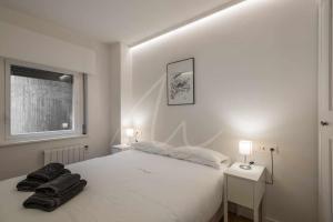 1 dormitorio con 1 cama blanca con 2 mesitas de noche y 2 lámparas en Saboredo by SeaMount Rentals en Naut Aran