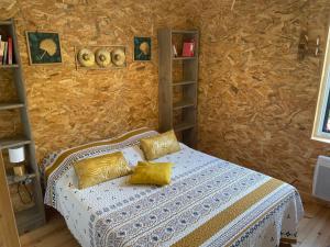 a bedroom with a bed with yellow pillows on it at GITE CHALET BOIS in Bessuéjouls