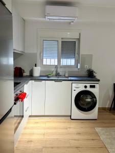 biała kuchnia z pralką w obiekcie City Centre Apartment w mieście Patras