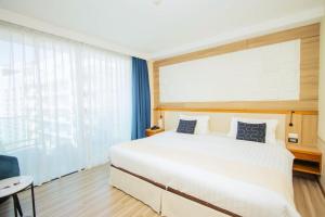 una camera da letto con un grande letto bianco con cuscini blu di Sira Grande Hotel & Spa a Patong Beach