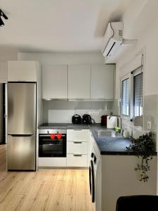 cocina con armarios blancos y nevera de acero inoxidable en City Centre Apartment, en Patra