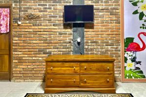 a wooden dresser with a television on top of it at TwoSpaces Living at Pondok Pakde, Jogja in Soprayan