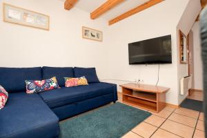 ein blaues Sofa im Wohnzimmer mit einem TV in der Unterkunft Apartmajske hiške Lubadarček in Podčetrtek