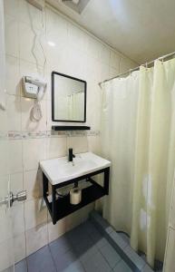 a bathroom with a sink and a mirror and a shower at Sukhavati Inn in Baguio