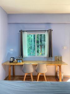 a bedroom with a table and two chairs in front of a window at Makorn Nonkleng in Ban Yung