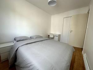 a white bedroom with a bed and a window at Appartement 6 places, 3 chambres in La Mulatière