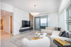 Stunning Views, Luxury Residence By Chi Living في دبي: غرفة معيشة مع أريكة بيضاء وتلفزيون