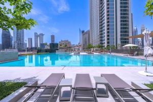 Stunning Views, Luxury Residence By Chi Living في دبي: مسبح كبير مع كراسي صالة وأفق المدينة