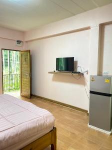 a bedroom with a refrigerator and a tv on the wall at Makorn Nonkleng in Ban Yung