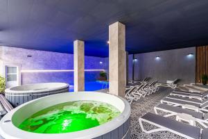 a large tub of green water in a room with chairs at Konopka Forest Home & SPA in Bukovel