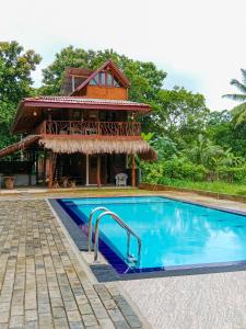 a villa with a swimming pool in front of a house at Sigiriya Elegant Resort in Sigiriya