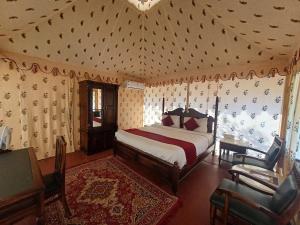 a bedroom with a bed and a chair and a window at Royal Pushkar Camps- a Luxury Camp Resort in Pushkar