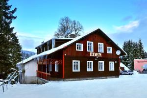 a red building with a sign on it in the snow at Chalupa EDEN Harrachov in Harrachov