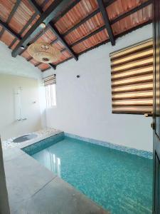 a swimming pool in a white room with a wooden ceiling at Camp TigerLily - Dudhwa in Bhīra